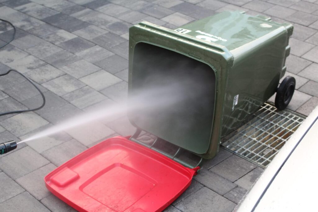 Cleaning the dustbin with horizontal position using water hose within the patio in Bin Cleaning Perth